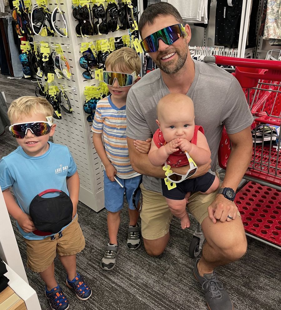 John with his three boys, all wearing oversized sunglasses